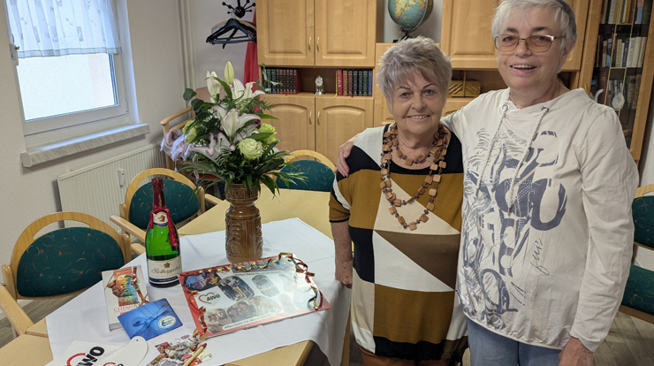 Zwei Frauen lächeln Arm in Arm in die Kamera.