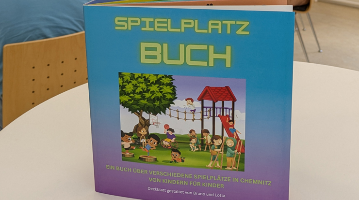 Elf Kinder und der Chemnitzer Oberbürgermeister halten das neue Spielplatzbuch in die Kamera.