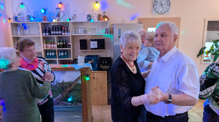 Unter Pavillons sitzen Menschen im Park und hören einem Sänger zu.